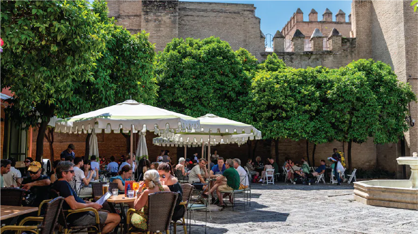 People dine outside on a sunny afternoon in Seville, Spain