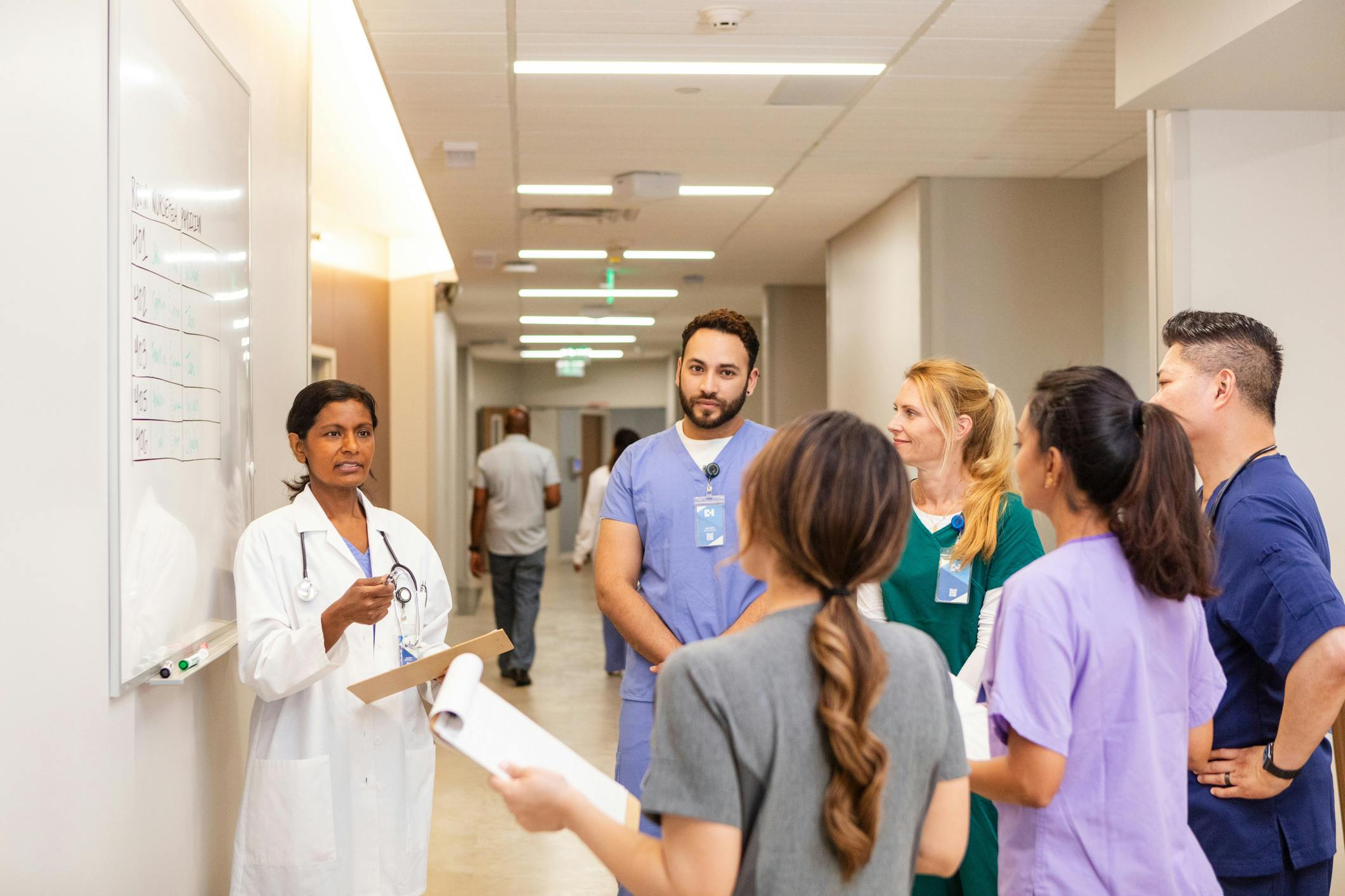 Medical interns receiving instruction and guidance from a medical processional in a hospital setting