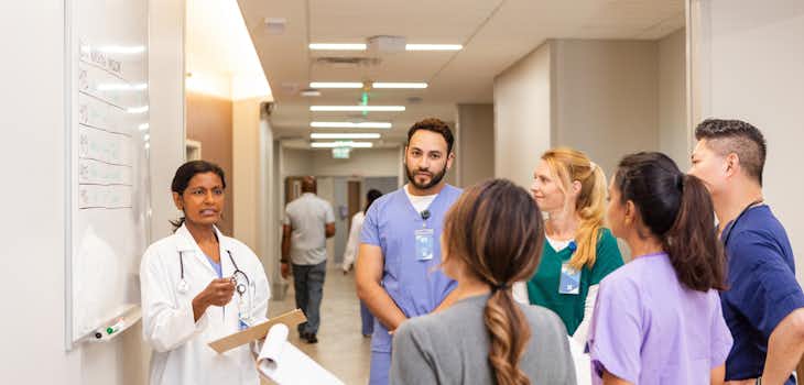 Medical interns receiving instruction and guidance from a medical processional in a hospital setting