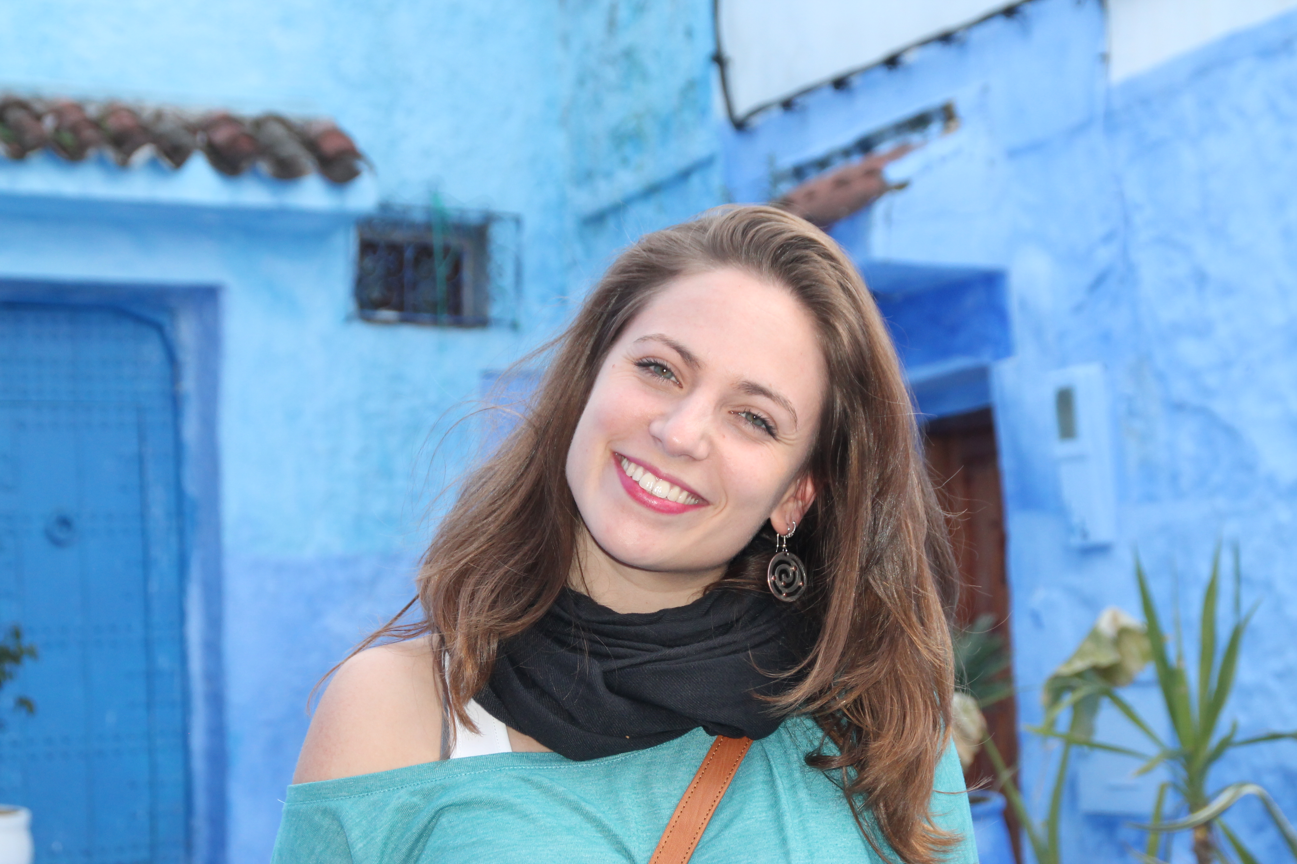 Female student intern standing against a blue building backdrop in the beautiful 