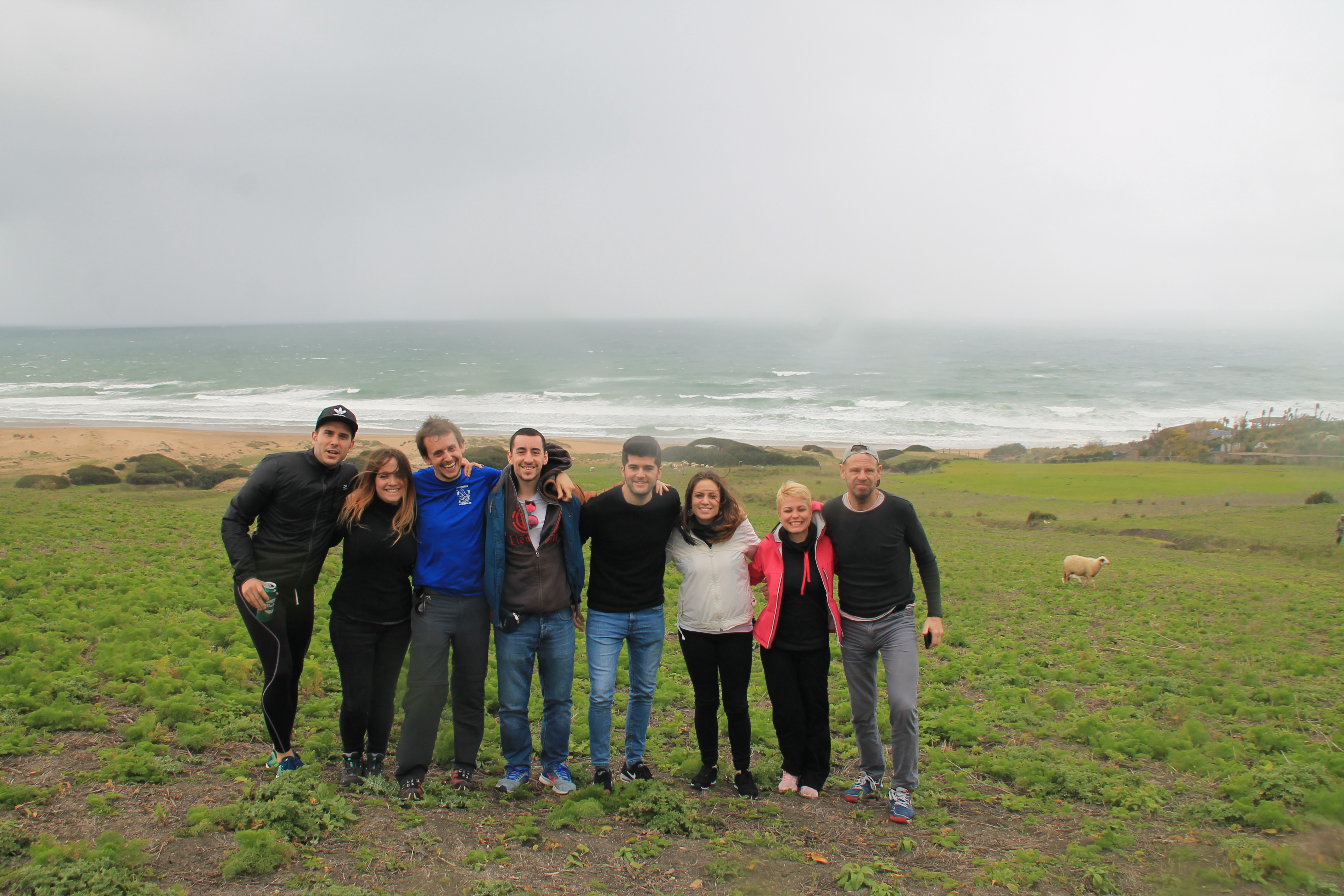 A mixed group of student interns in Morocco, standing together in a green field, next to the coast
