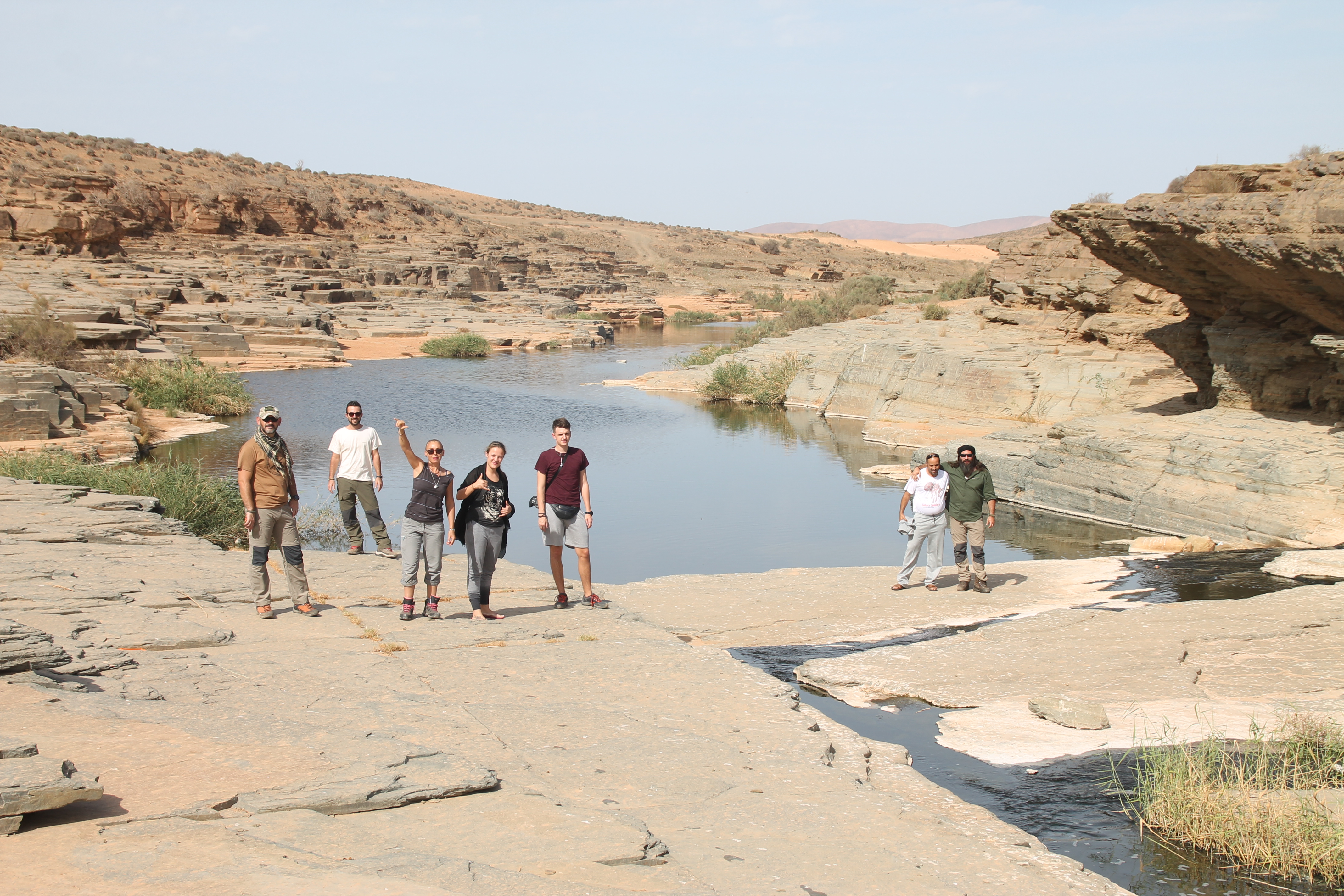 A mixed group of student interns in Morocco, standing together next to a shallow river