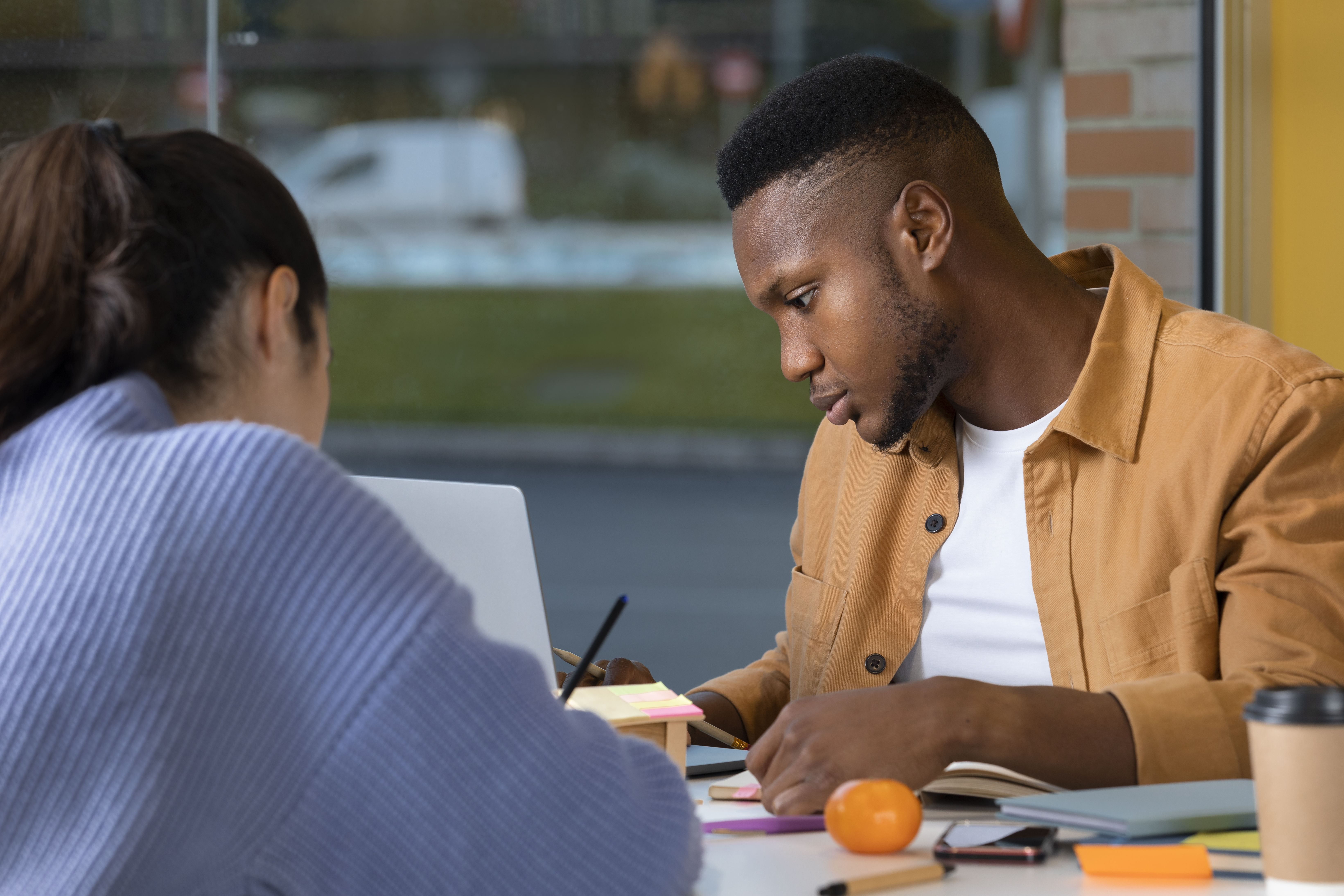 A social work student participates in an internship experience, he reviews information online, in an office, with a fellow social worker