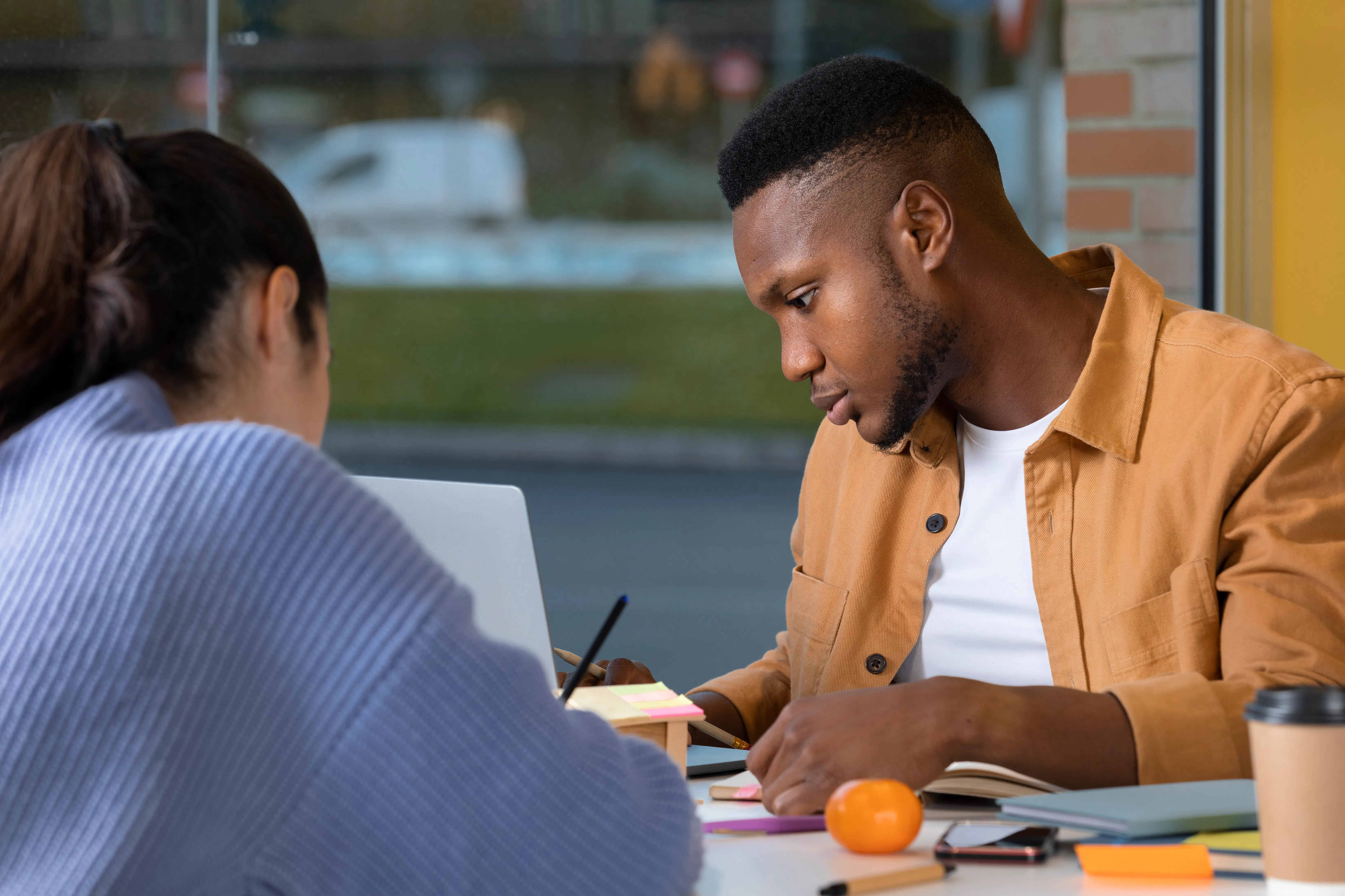 A social work student participates in an internship experience, he reviews information online, in an office, with a fellow social worker