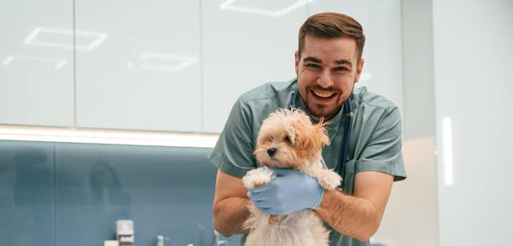 A vet poses with a cute dog inside a veterinary clinic